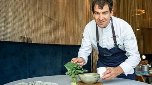 Chef garnishing gourmet soup in a ceramic bowl at a fine dining restaurant