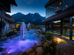 Luxushotel-Spa mit beleuchtetem Außenpool und Bergblick in der Dämmerung