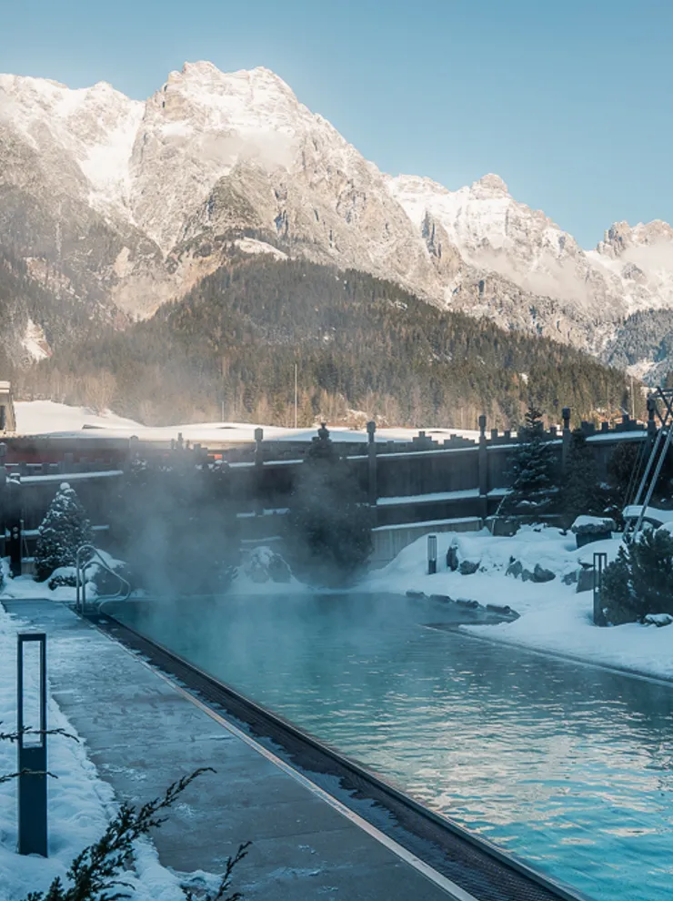 Thermalbecken im Freien in verschneitem Alpinresort mit Bergblick
