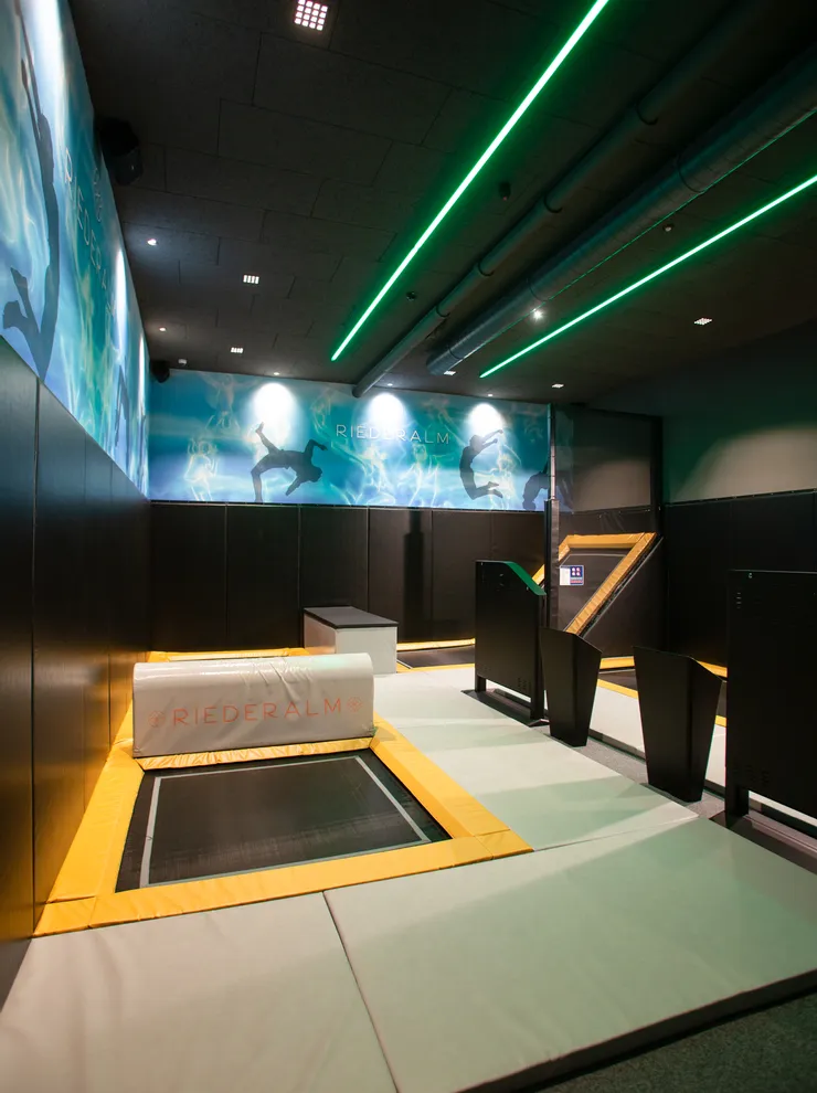 Indoor-Trampolinpark bei Riederalm mit gepolsterten Böden und Neonbeleuchtung