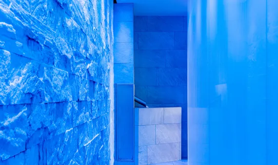 Modern spa corridor with blue ambient lighting and stone walls