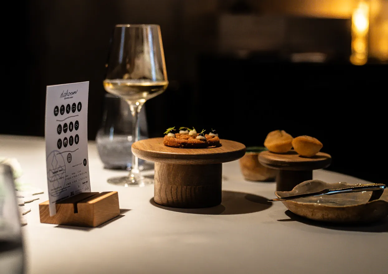 Gourmet-Vorspeisen auf Holzplatten mit Weingläsern auf einem Fine-Dining-Tisch