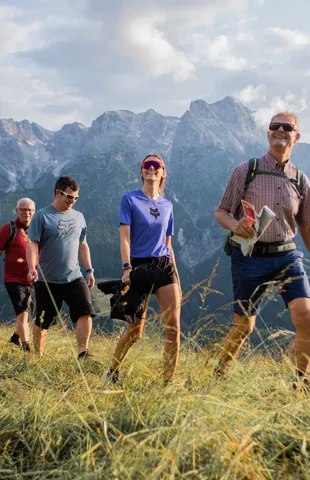 Group of hikers walking on a grassy trail with scenic mountain view in the background