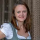 Frau in traditionellem bayerischen Dirndl lächelt vor Kettenvorhang