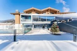 Modernes Hotel mit Glasfassade und Außenpool im verschneiten Winterurlaubsort