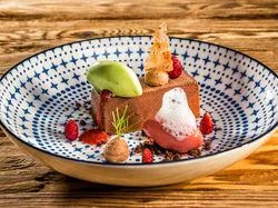 Gourmet chocolate dessert with strawberry sauce, green sorbet, and foam in decorative plate