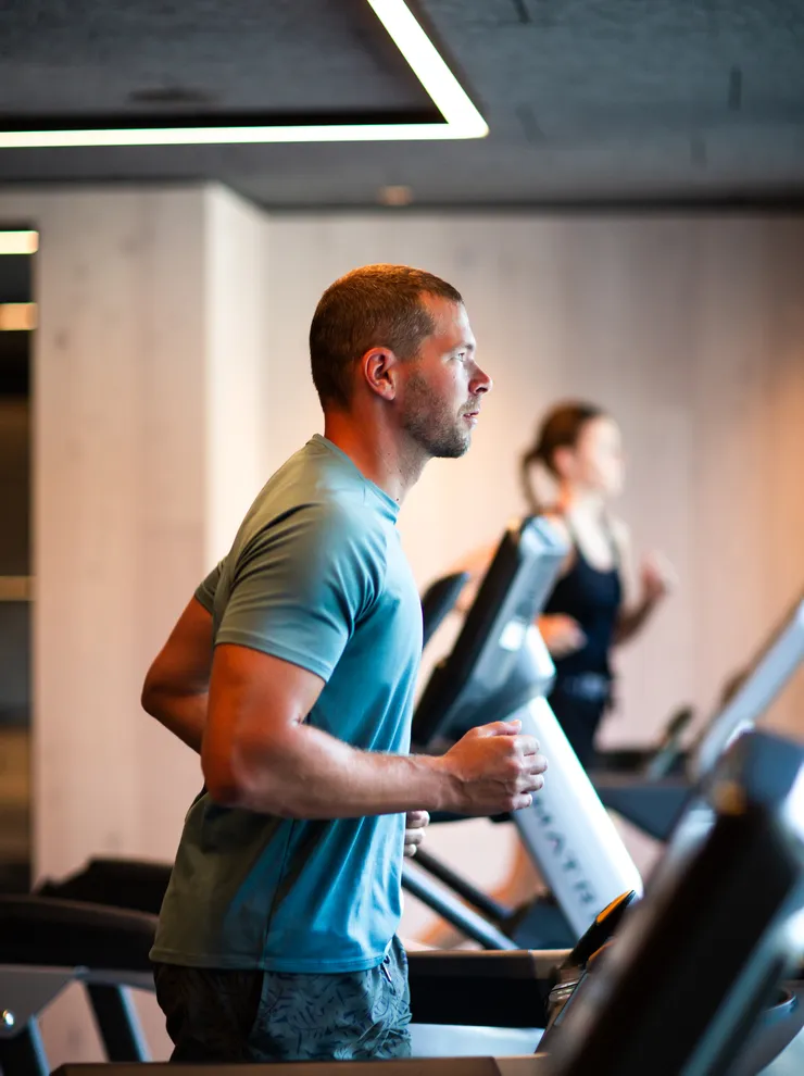 Mann trainiert auf einem Laufband im modernen Fitnessstudio