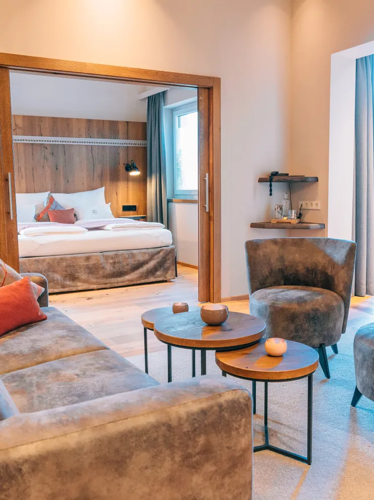 Modern hotel suite with lounge area, velvet armchairs and a cozy bed in natural light