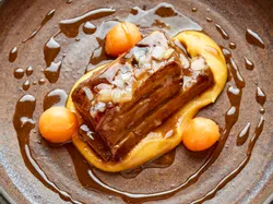 Braised pork belly with pumpkin purée and melon balls in a rich glaze
