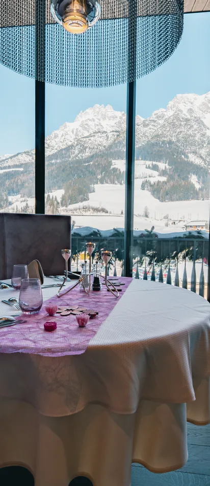 Gedeckter Restauranttisch mit Panoramablick auf verschneite Alpenlandschaft