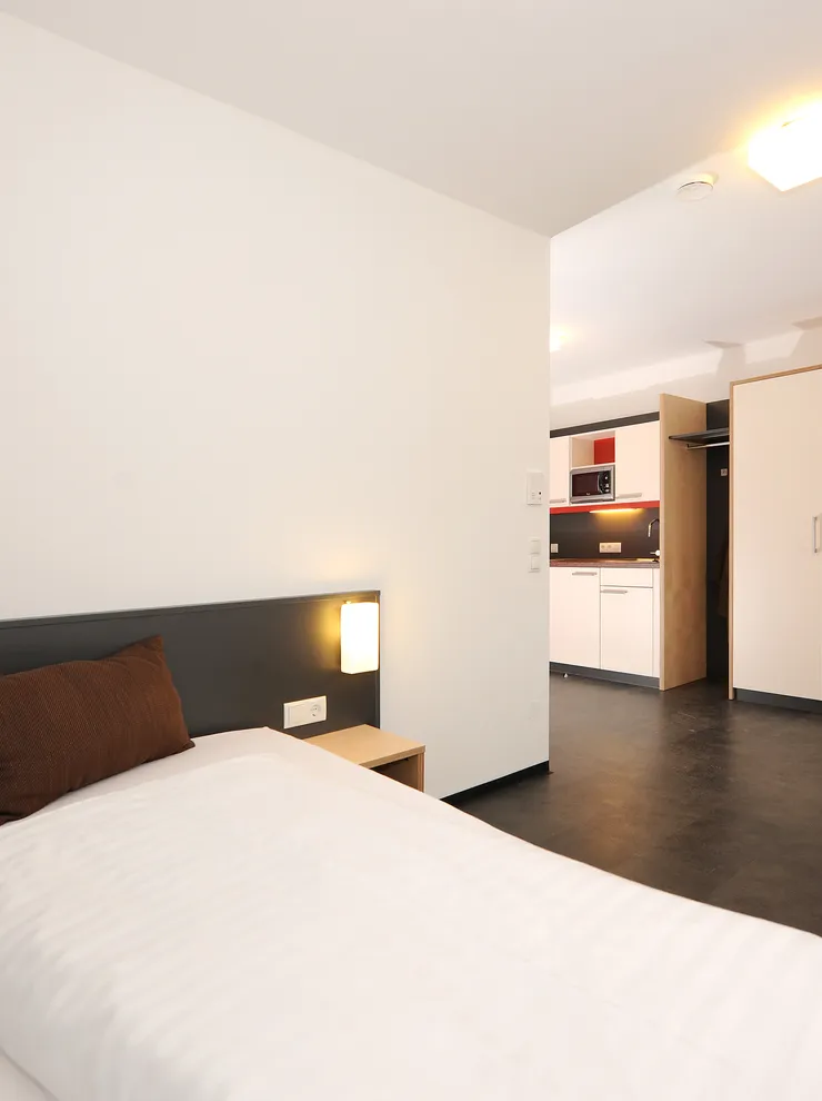 Modern student apartment with bed, kitchenette, wardrobe and study desk