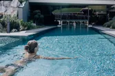 Woman swimming in luxury hotel outdoor pool with mountain view