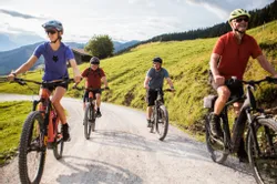 Group of cyclists riding on gravel road through green hills on a sunny day