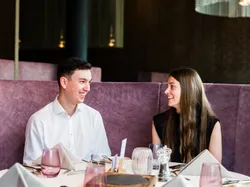 Young couple smiling at each other in a stylish restaurant with a set dining table