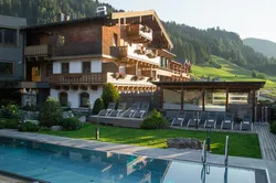 Luxuriöses Alpenhotel mit Außenpool und Bergblick bei Sonnenuntergang