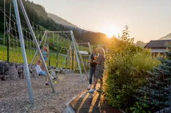 Family at mountain playground during sunset with swings and drinks