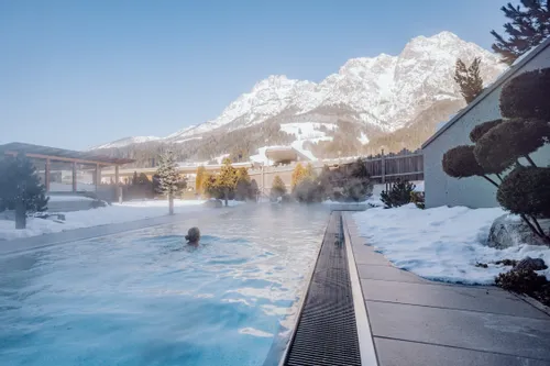 Außen-Thermalbecken im Schnee mit Bergblick in einem alpinen Resort