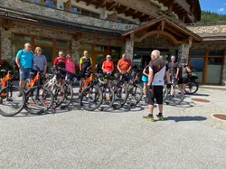 Gruppe von Radfahrern mit Mountainbikes vor einer rustikalen Lodge bei sonnigem Wetter