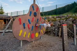 Child playing on a colorful climbing wall with foot and hand grips at outdoor playground