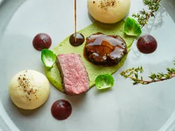 Gourmet-Rindfleischgericht mit Soße, Kartoffelkuppeln, Erbsenpüree und Rosenkohl auf Designer-Teller