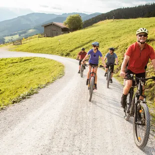 Group of cyclists riding mountain bikes on a gravel path through scenic countryside