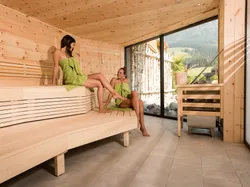 Zwei Frauen entspannen in moderner Holzsauna mit Bergblick