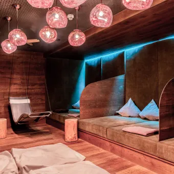 Moderner Spa-Ruheraum mit warmem Licht, Hängesesseln und gepolsterten Liegeflächen