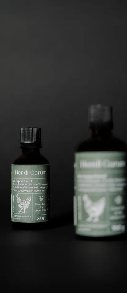 Two bottles of Hendl Garum organic soup seasoning with green labels on black background