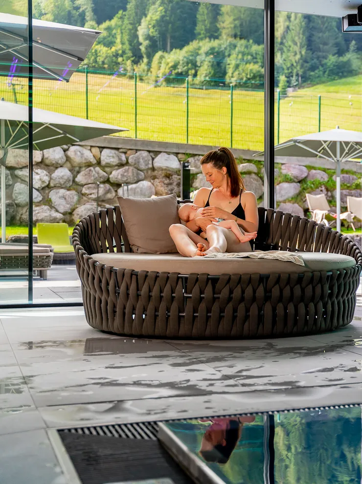 Mutter stillt Baby am Innenpool mit malerischem Bergblick