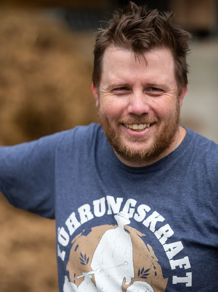Smiling bearded man wearing a blue T-shirt with 'Führungskraft' printed on it