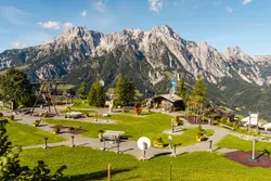 Playground with wooden huts and stunning alpine mountain backdrop on a sunny day