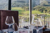 Elegant restaurant table set with wine glasses overlooking scenic mountain landscape