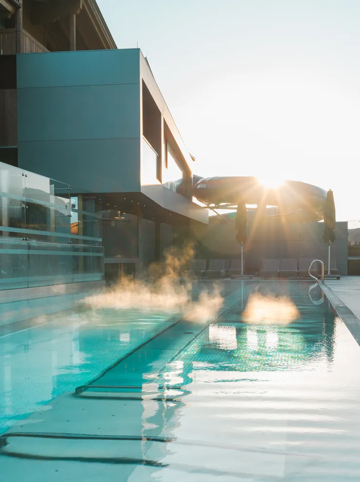 Steam rising from heated outdoor pool at modern hotel during sunrise