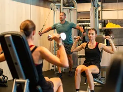 Mann und Frau machen Krafttraining in einem modernen Fitnessstudio mit Spiegeln