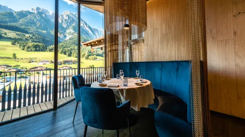 Elegantes Restaurant mit Bergblick, rundem Tisch und blauer Samtsitzbank