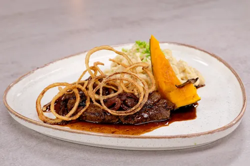 Gebratene Leber mit Röstzwiebeln, Kürbis und Spätzle auf Keramikteller serviert
