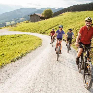 Group of cyclists riding mountain bikes on a gravel path through scenic countryside