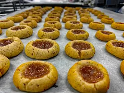 Freshly baked thumbprint cookies with jam filling on a parchment-lined baking tray