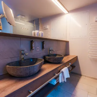 Modern bathroom with dual stone sinks on a wooden vanity and soft ambient lighting