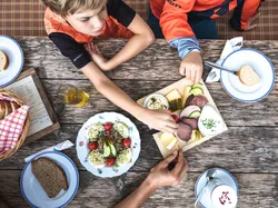 Children sharing traditional cold platter with cheese, cold cuts and bread on rustic wooden table