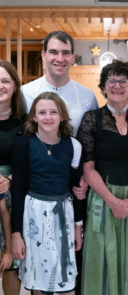 Smiling family in traditional attire and chef apron in a hotel restaurant setting
