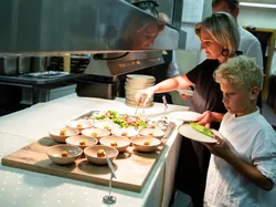Woman and boy picking up plated appetizers and salad at a restaurant buffet station