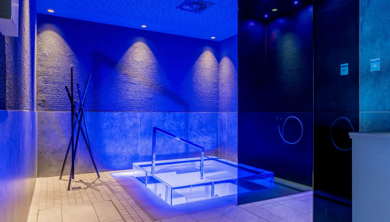 Modern spa with illuminated plunge pool and blue ambient lighting